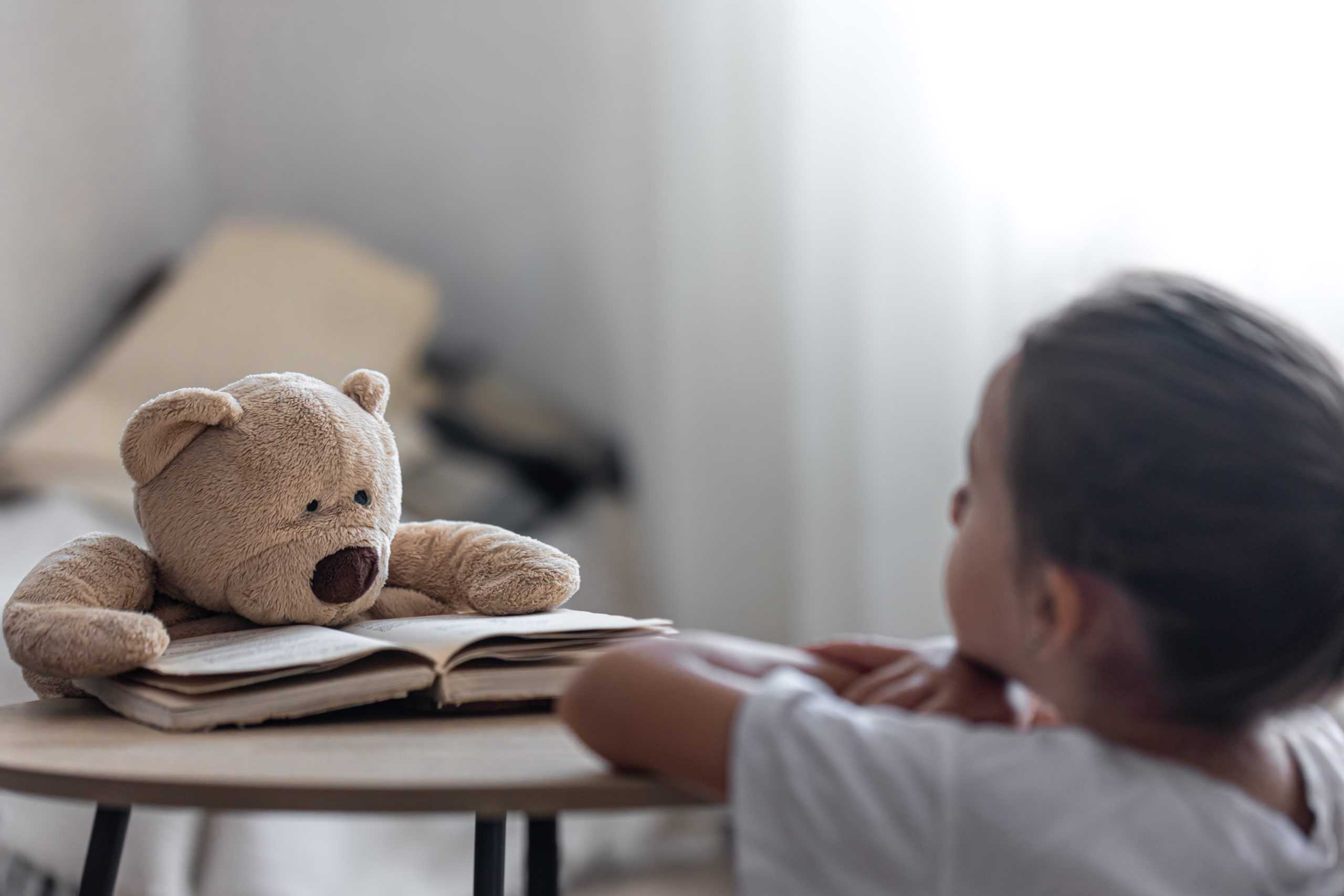 a-little-girl-plays-with-her-teddy-bear-and-a-book-teaches-him-to-read-plays-at-school-scaled