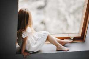 little-child-in-tender-white-dress-is-sitting-on-the-windowsill-300x200